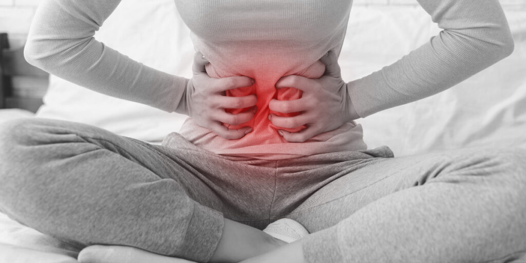 A woman with stomach pain sitting on a bed